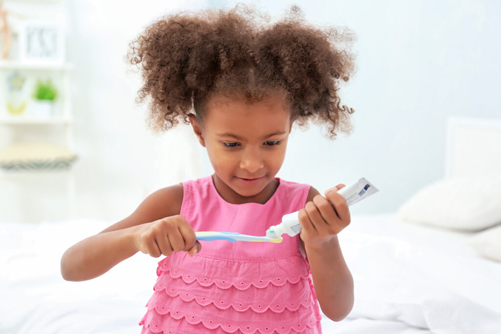 Cute African American girl brushing teeth